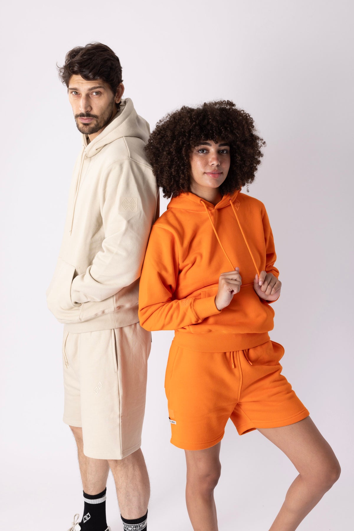 Models wearing Double Black Experts Only Sweatshorts in orange and cream