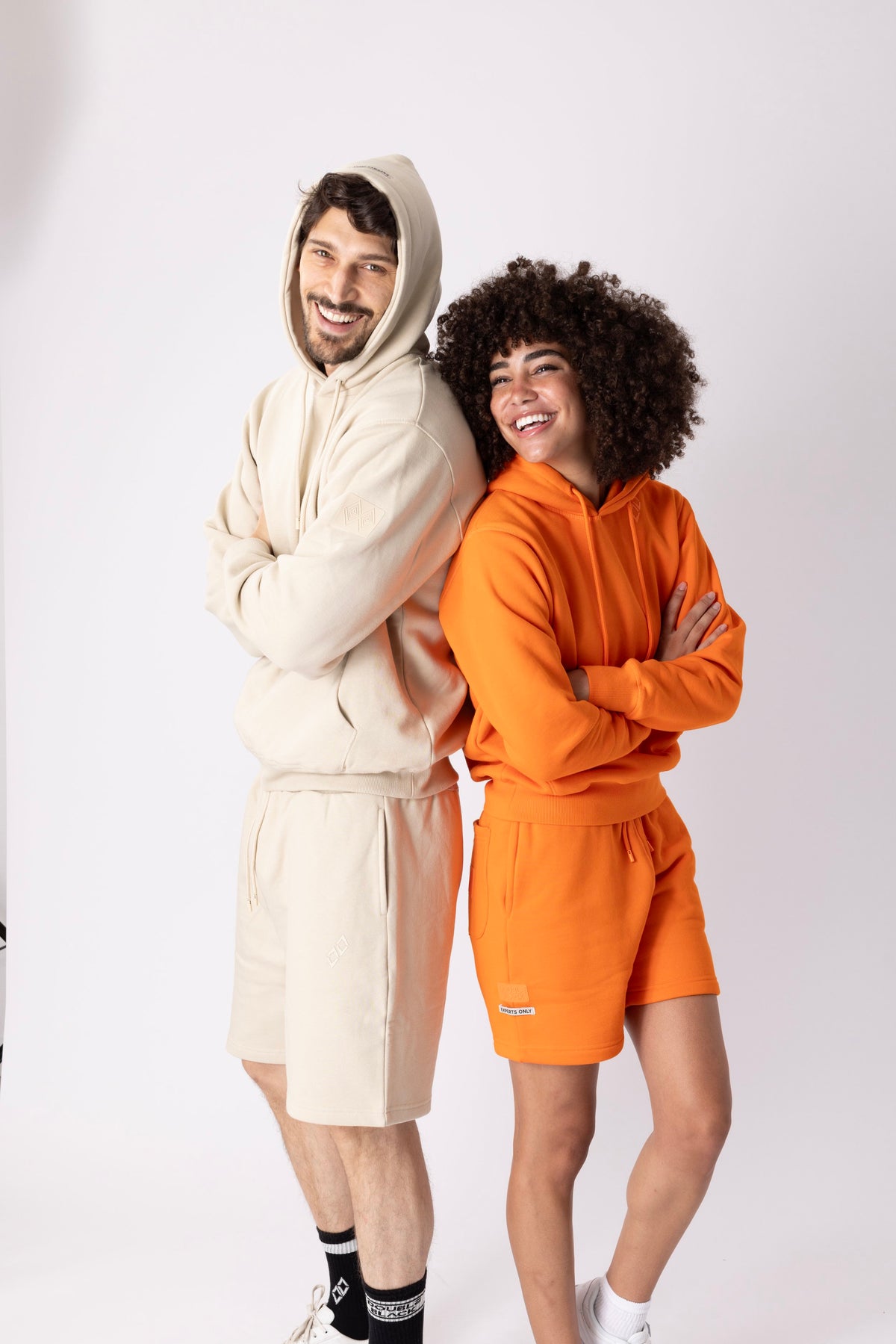 Models wearing Double Black Experts Only Sweatshorts in orange and cream