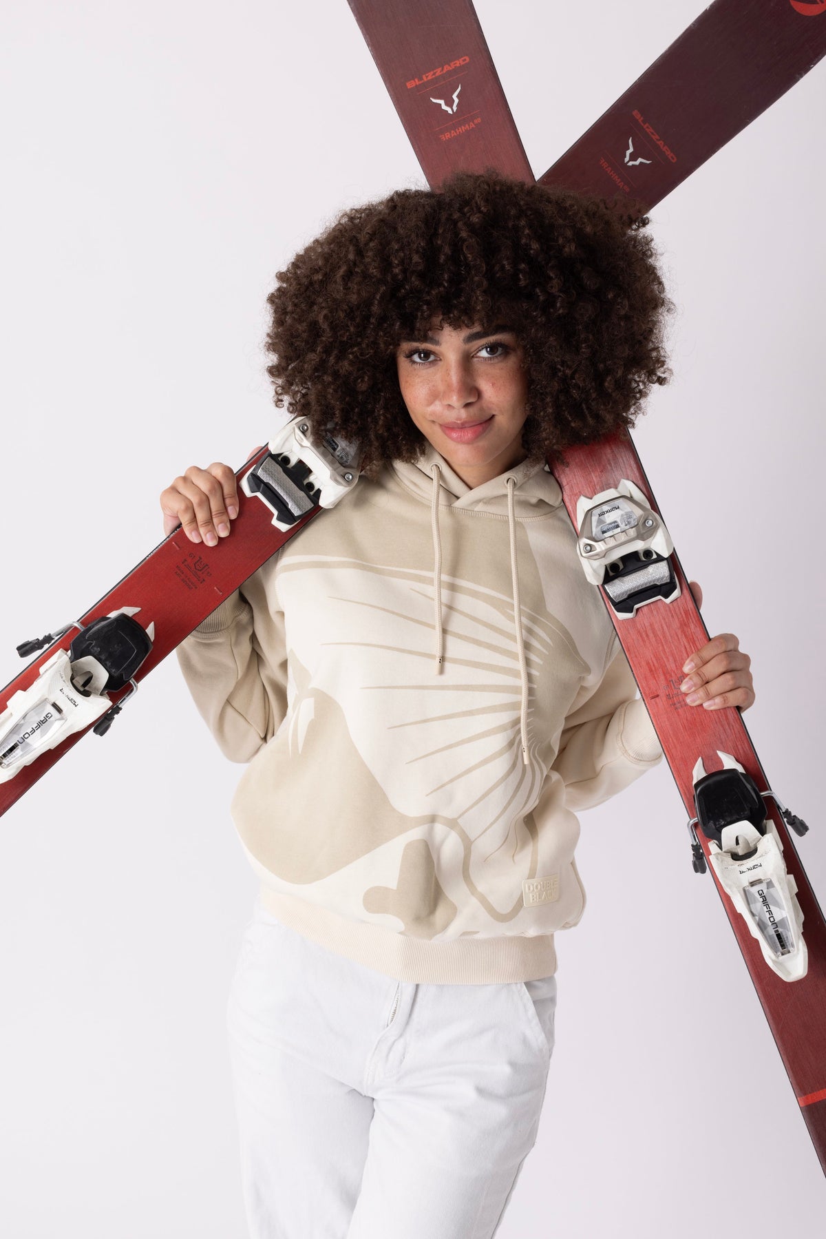 Model wearing Double Black On The Mountain Hoodie in cream with skis 