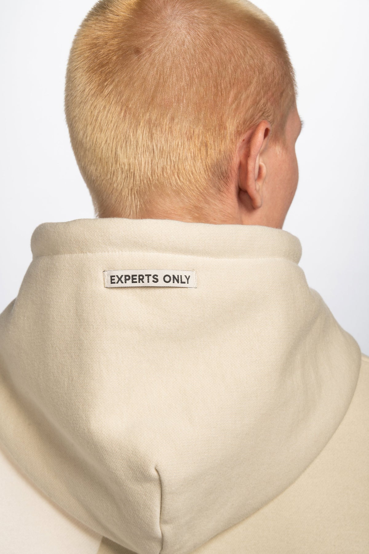 Model wearing Double Black On The Mountain Hoodie in cream with Experts Only hood label