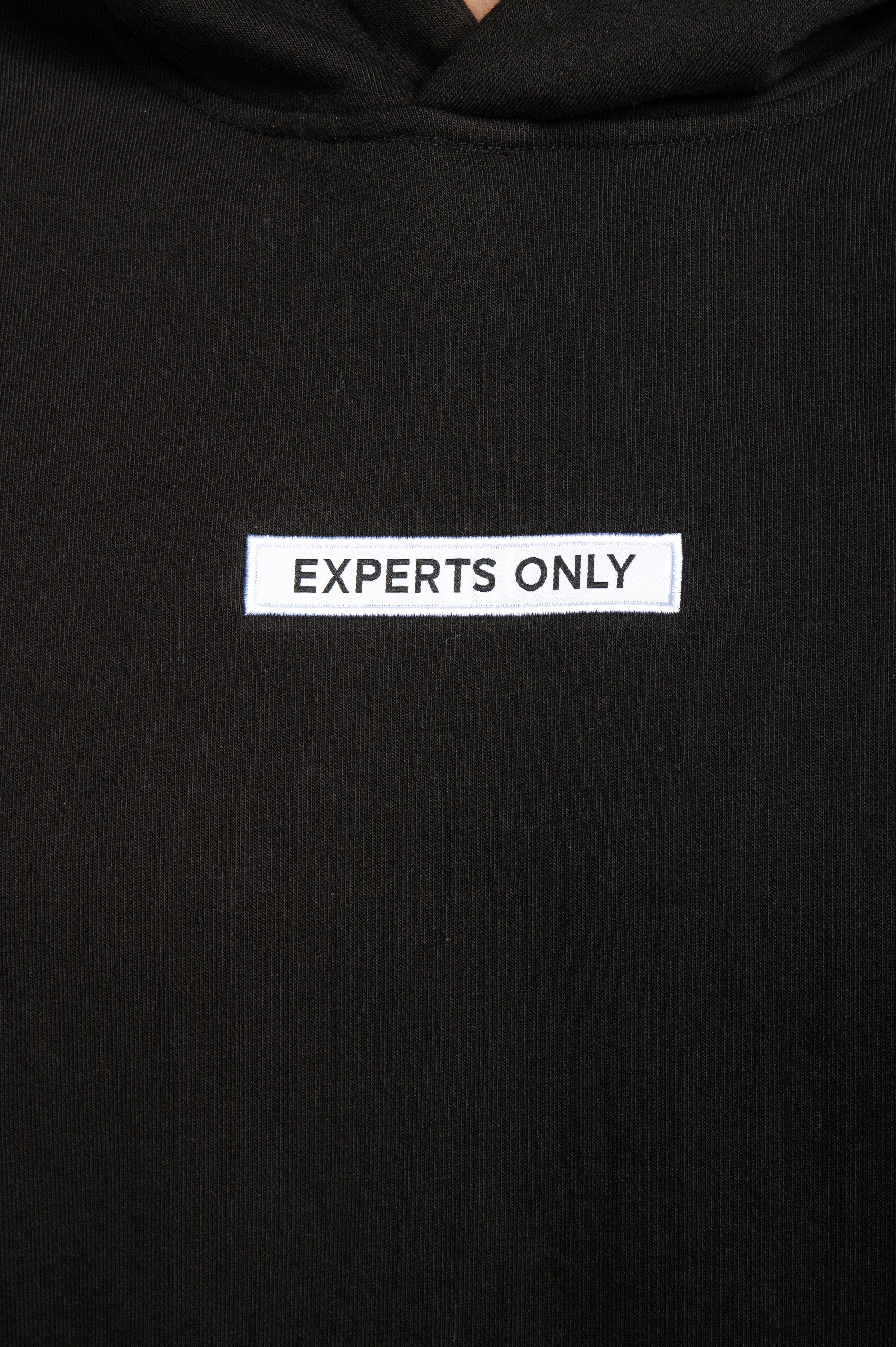 Detailed view of 'Experts Only' front patch on Black hoodie