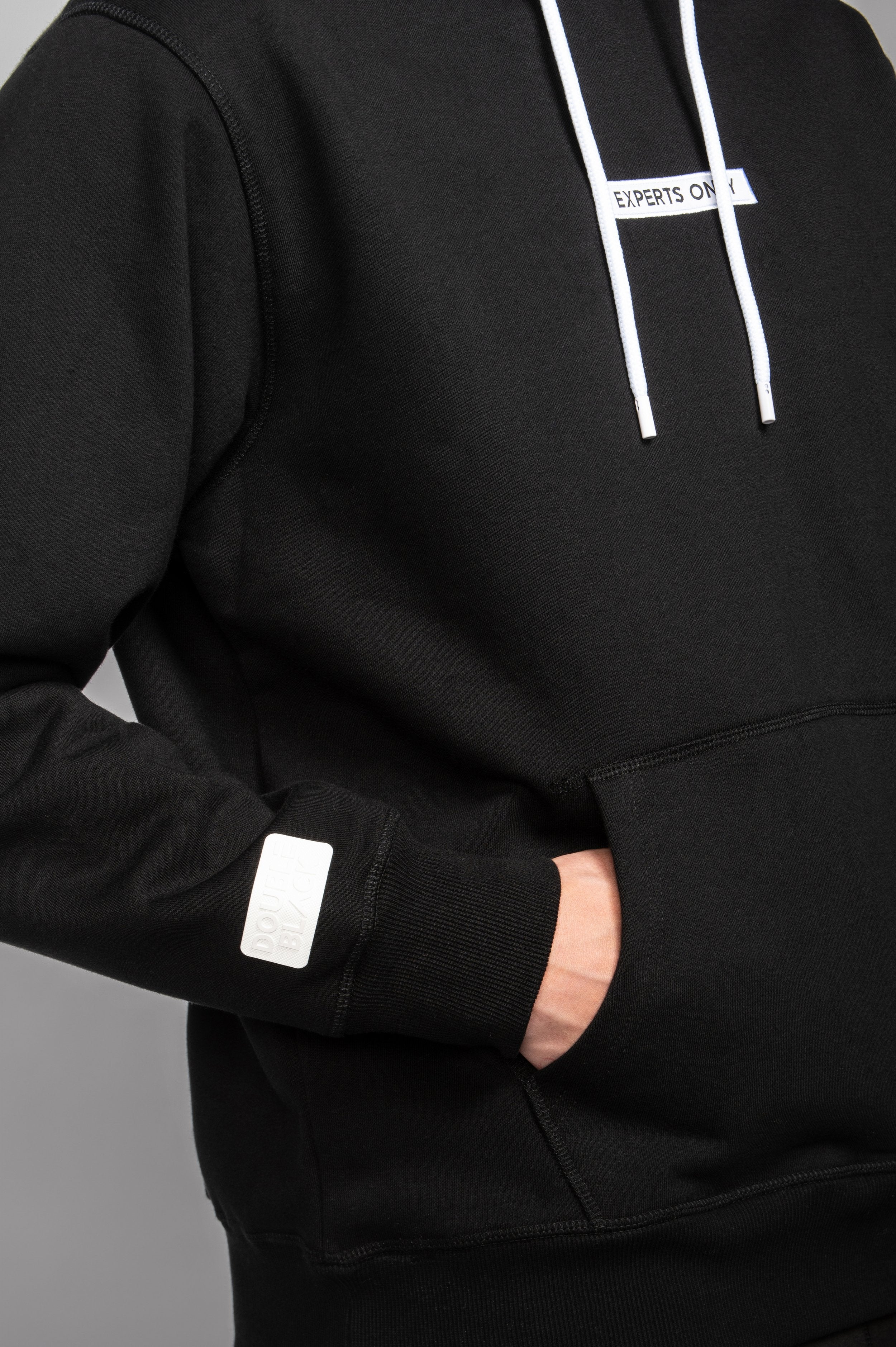 Close-up of silicone sleeve patch on Black Experts Only Hoodie