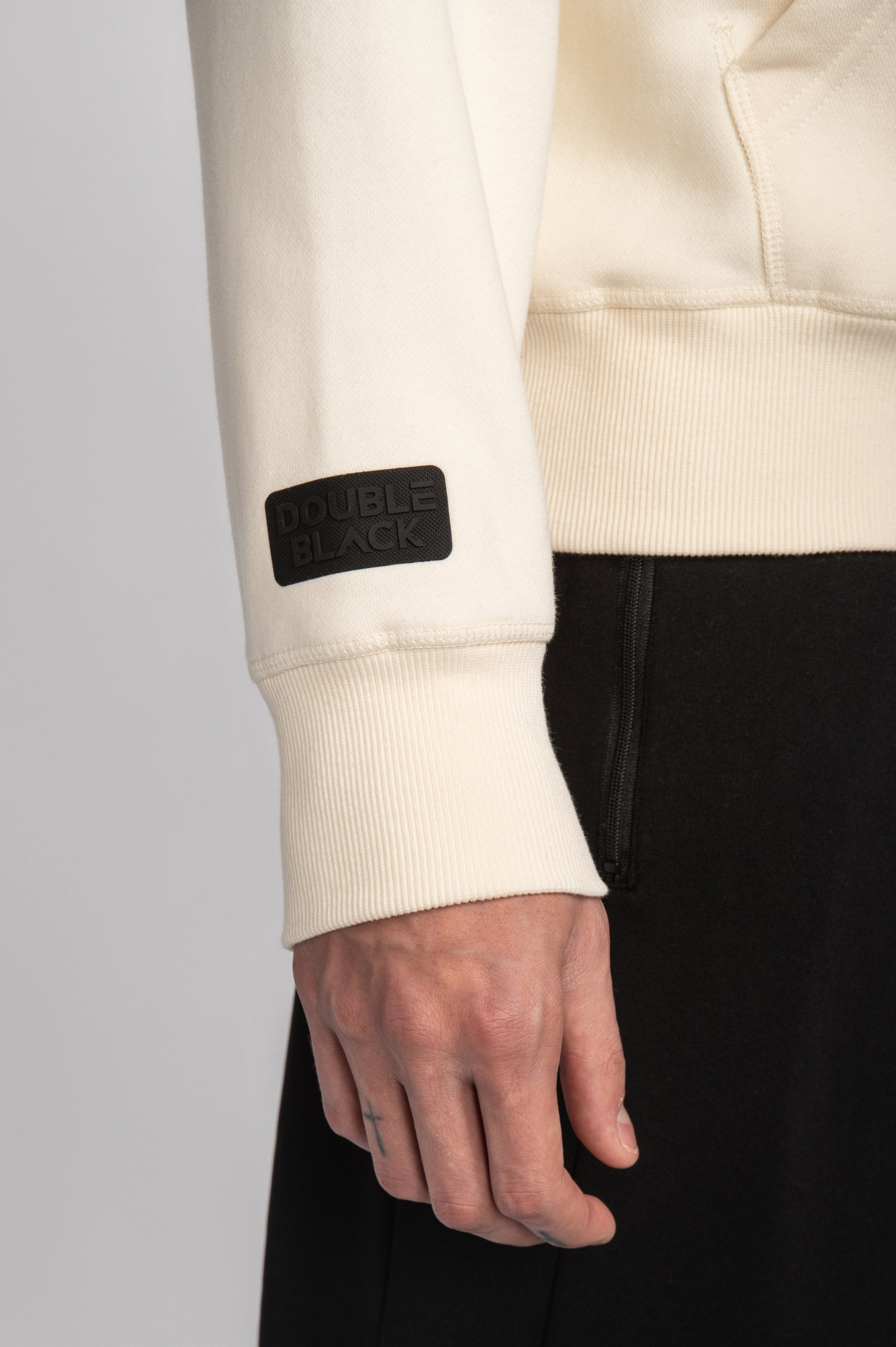 Close-up of silicone sleeve patch on Cream Experts Only Hoodie