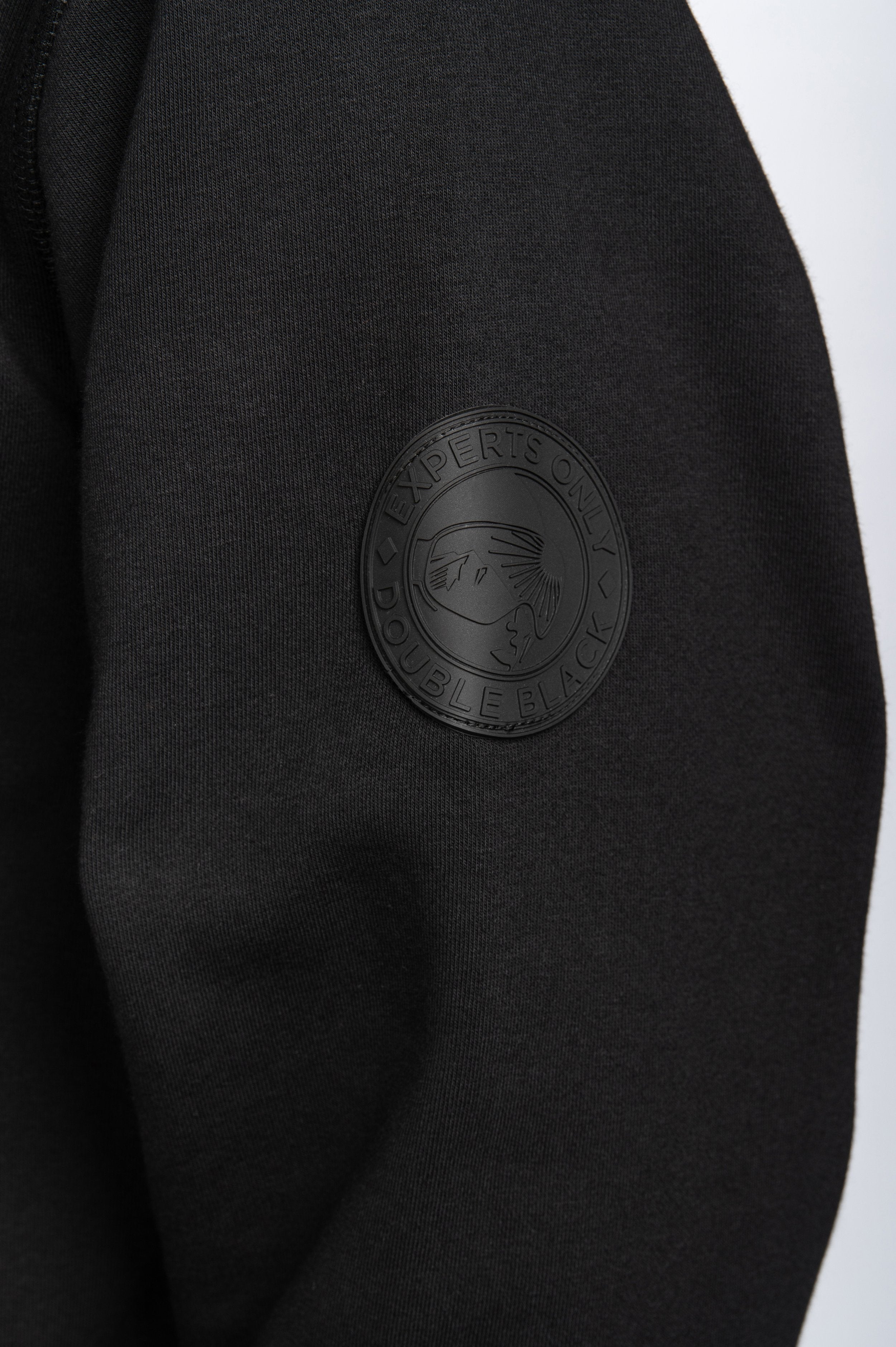 Model wearing Double Black Hoodie in black sleeve patch